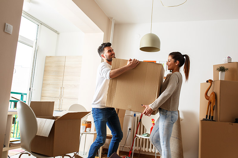 Young,Couple,Carrying,Big,Cardboard,Box,At,New,Home.moving,House.